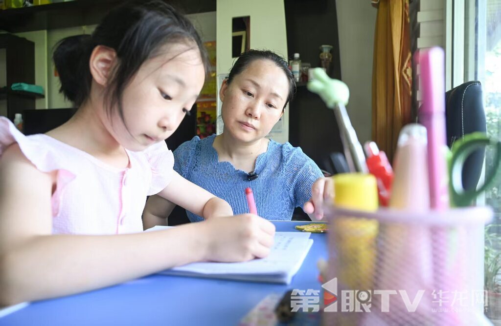 白时玲监督女儿作业。 